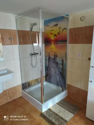 a shower in a bathroom with a painting on the wall at Apartament Anna in Bachowice