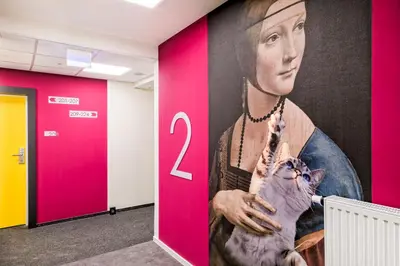 a wall with a painting of a woman holding a cat at Easy One Premium Art in Kraków