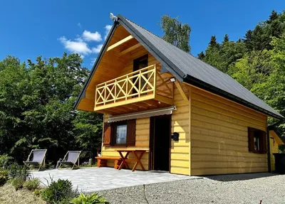 a cabin with a deck and two chairs in front at Domek Bogdanówka in Pisarzowa