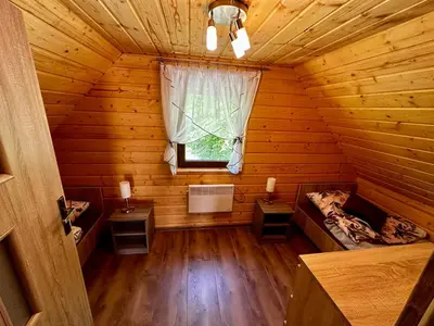 an attic room of a log cabin with a window at Domek Bogdanówka in Pisarzowa