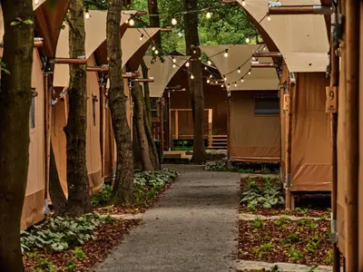 a walkway through a tent yard with string lights at Zatoria Luxury Glamping ZATOR in Zator
