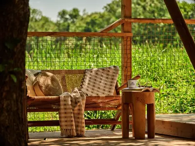 a person sitting in a chair on a porch with a table at Zatoria Luxury Glamping ZATOR in Zator