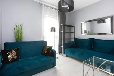 a living room with a blue couch and a glass table at Margaret Apartment in Kraków