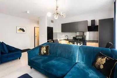 a living room with a blue couch and a kitchen at Margaret Apartment in Kraków