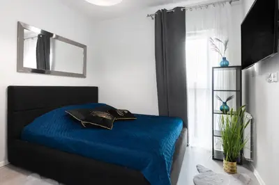 a bedroom with a blue bed and a mirror at Margaret Apartment in Kraków
