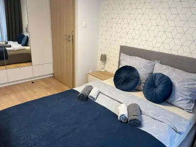 a bedroom with a bed with blue pillows on it at Rakowicka Modern Apartment in Kraków