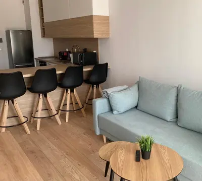 a living room with a couch and chairs and a kitchen at Rakowicka Modern Apartment in Kraków