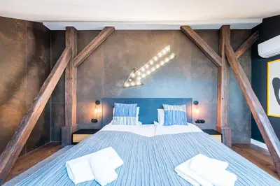 a bedroom with a large blue bed with wooden beams at Wegierska Luxury Loft WAWELOFTS in Kraków