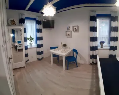 a dining room with a table and blue and white curtains at Capitals Residence in Oświęcim