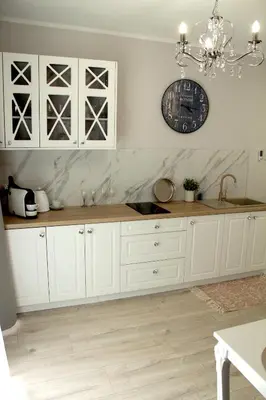 a kitchen with white cabinets and a clock on the wall at Capitals Residence in Oświęcim
