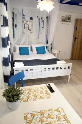 a bedroom with a white bed with blue pillows at Capitals Residence in Oświęcim