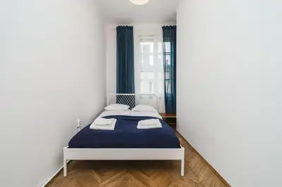 a bedroom with a blue bed in a white room at Apartments in The Jewish Quarter - LOW STANDARD - 10' Main Square - by Upstairs in Kraków