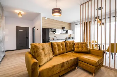 a living room with a brown couch and a kitchen at Rakowicka Old Town Luxury Apartments WAWELOFTS in Kraków