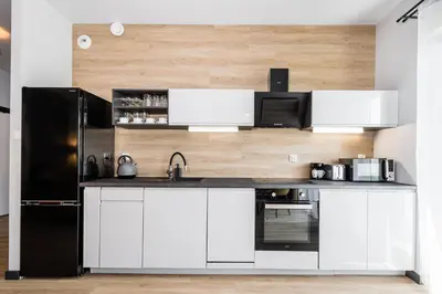 a kitchen with white cabinets and a black refrigerator at Rakowicka Old Town Luxury Apartments WAWELOFTS in Kraków