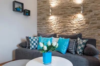 a couch with pillows and a vase with flowers on a table at Neo Apartments in Kraków
