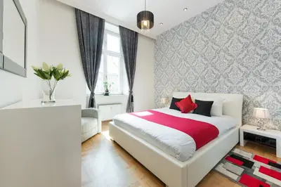 a bedroom with a white bed with red pillows at Neo Apartments in Kraków