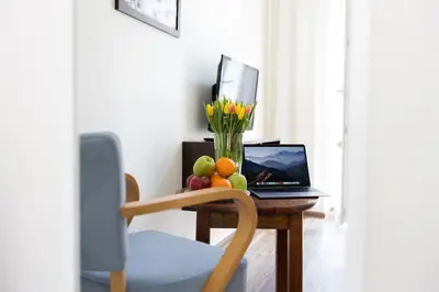 a table with a laptop and fruit and a vase of flowers at Salve station in Kraków