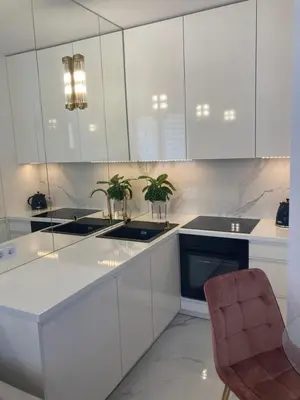 a kitchen with white cabinets and a chair in it at Apartamenty Parkowe B18 in Oświęcim