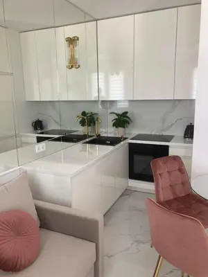 a kitchen with white cabinets and two chairs and a couch at Apartamenty Parkowe B18 in Oświęcim