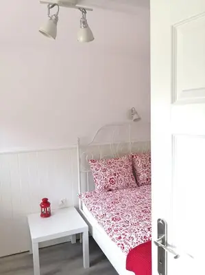 a bedroom with a bed with pink pillows and a table at Red Bed in Jankowice