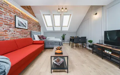 a living room with a red couch and a brick wall at Saint Florian's Suites - Old Town Luxury Apartments - by Upstairs in Kraków
