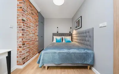 a bedroom with a brick wall and a bed with blue pillows at Saint Florian's Suites - Old Town Luxury Apartments - by Upstairs in Kraków