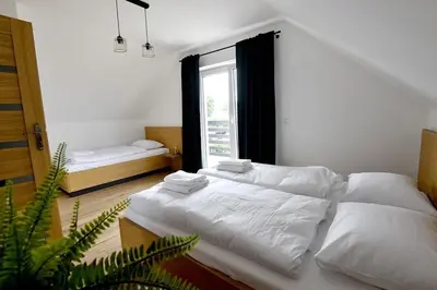 a white bedroom with two beds and a window at Domki na Krótkiej in Spytkowice