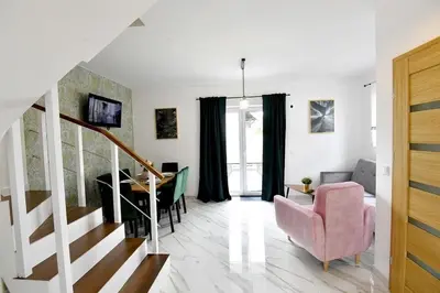 a living room with a staircase and a pink chair at Domki na Krótkiej in Spytkowice