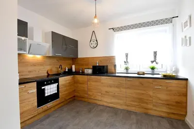 a large kitchen with wooden cabinets and a window at Domki na Krótkiej in Spytkowice