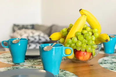 a bowl of fruit on a table with blue cups at ENERGYLANDIA Zator Apartament Krzyś in Zator