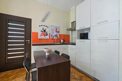 a kitchen with white cabinets and a wooden table at Urban Nest Apartments Dietla 69 in Kraków