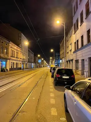 a city street at night with cars parked on the street at Kalwaryjska Spot Apartment in a Good Location in Kraków