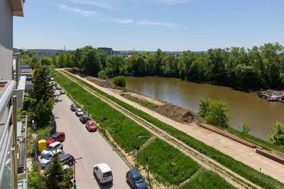 a street with cars parked next to a river at Apartment Na Zakolu Wisły by Noclegi Renters in Kraków