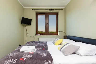 a bedroom with a bed with white sheets and a window at Apartment Na Zakolu Wisły by Noclegi Renters in Kraków