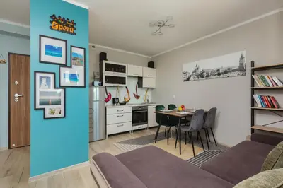 a kitchen and living room with a couch and a table at Apartment Na Zakolu Wisły by Noclegi Renters in Kraków