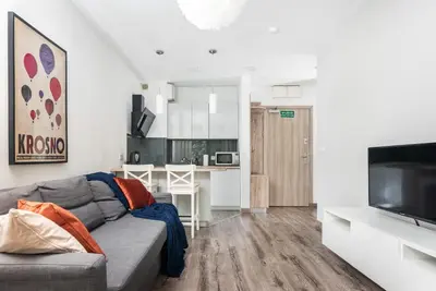 a living room with a gray couch and a kitchen at Blossom - Old Town Residence - by Upstairs in Kraków