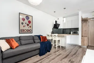 a living room with a couch and a kitchen at Blossom - Old Town Residence - by Upstairs in Kraków