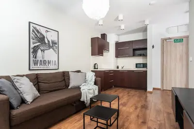 a living room with a couch and a kitchen at Blossom - Old Town Residence - by Upstairs in Kraków