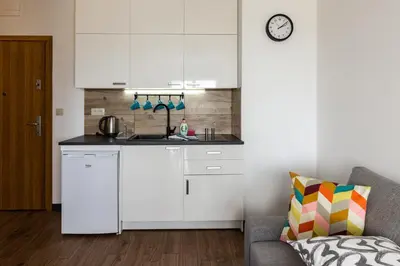 a kitchen with white cabinets and a couch in a room at ENERGYLANDIA Zator Apartament Grześ in Zator