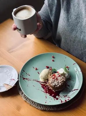 a person holding a cup of coffee and a plate of food at Villa & Gospoda Krakowska in Kobiernice