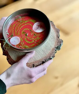 a person holding a bowl of soup on a table at Villa & Gospoda Krakowska in Kobiernice