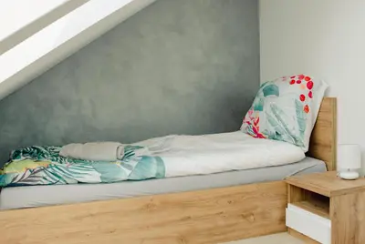 a bed under the stairs in a bedroom at Apartamenty Jordanów - Stacja Paliw MOYA in Jordanów