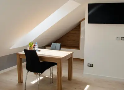 a dining room with a wooden table and chairs at Apartamenty Jordanów - Stacja Paliw MOYA in Jordanów