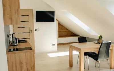 a kitchen and dining room with a table and a staircase at Apartamenty Jordanów - Stacja Paliw MOYA in Jordanów
