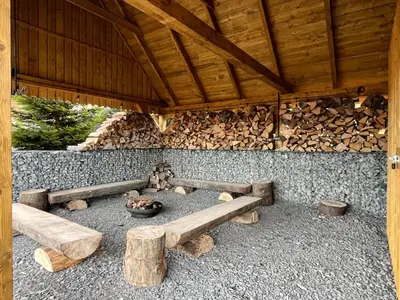 a building with a table and benches and logs at Chatka_Kasina in Kasina Wielka