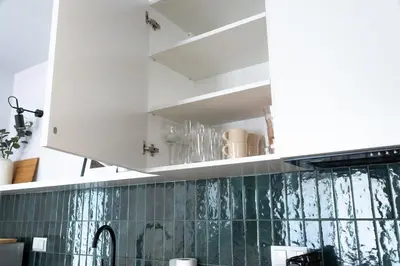a kitchen with white cabinets and green tiles at Riviera Camp in Radłów