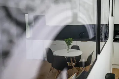 a table with chairs and a vase with a plant at Native Apartments Paulińska 20 Deluxe in Kraków