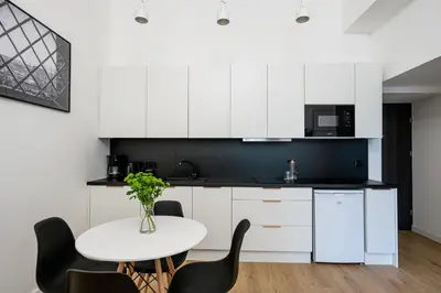 a kitchen with white cabinets and a white table and chairs at Native Apartments Paulińska 20 Deluxe in Kraków