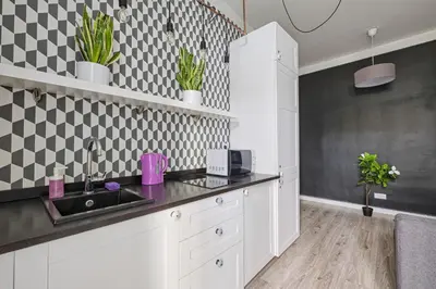 a kitchen with white cabinets and black and white tiles at Urban Nest Apartments Blich 8 in Kraków