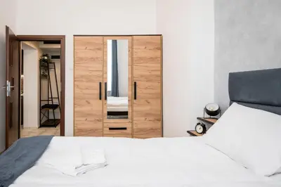 a bedroom with a white bed and a wooden door at Dajwor Residence Jewish Quarter WAWELOFTS in Kraków